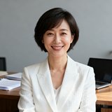某知名美妆品牌市场总监职业照：一位短发女性穿着白色西装外套，面带微笑，背景是简约的办公室环境。
