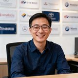 新能源汽车品牌公关经理的头像：一位戴眼镜的男士穿着深蓝色衬衫，坐在办公桌前微笑，身后是品牌logo展示墙。
